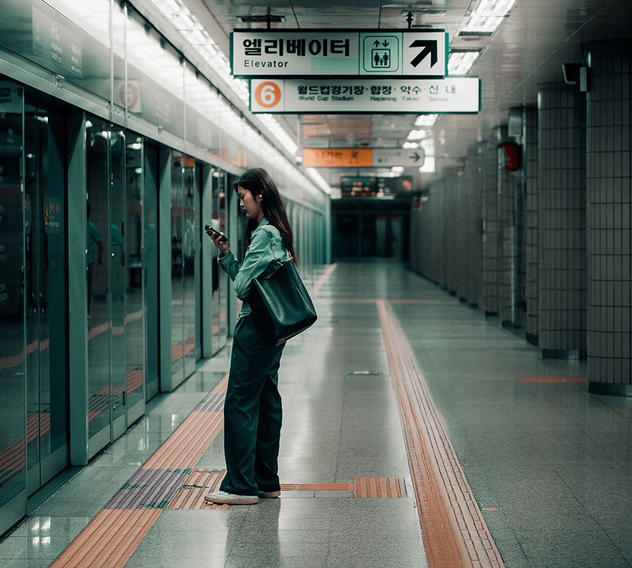 Woman checking her phone on a Seoul subway platform